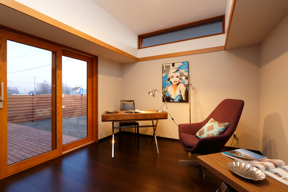 Ejemplo de despacho actual con paredes blancas, suelo de madera oscura, escritorio independiente y suelo marrón