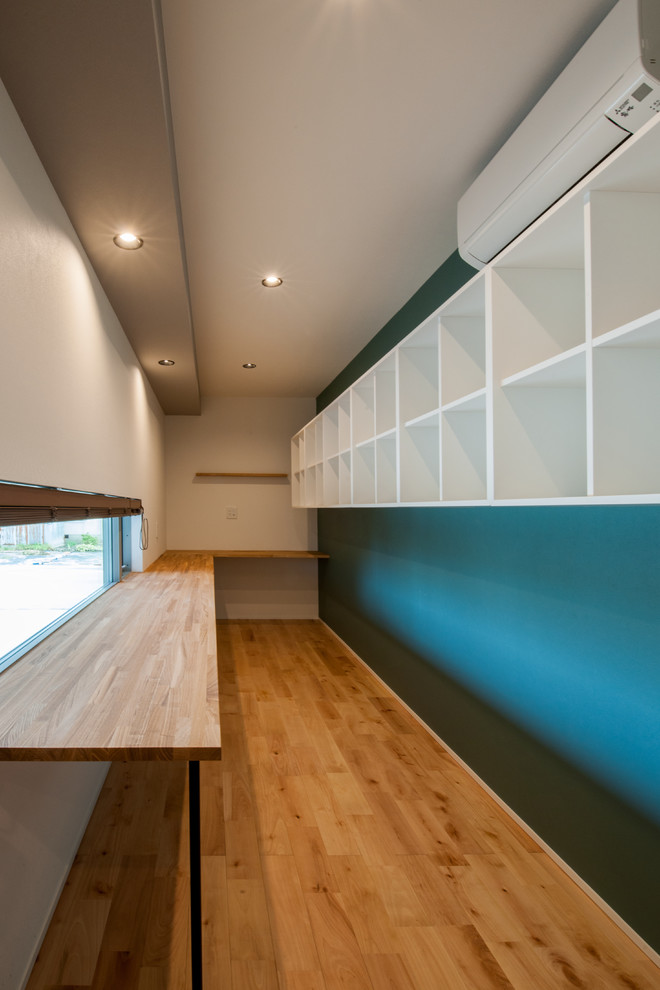 Réalisation d'un bureau vintage avec un mur bleu, parquet clair, aucune cheminée, un bureau intégré et un sol beige.