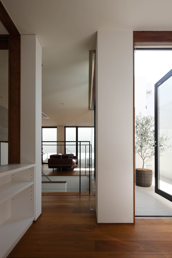 Ejemplo de despacho minimalista de tamaño medio con paredes blancas, suelo de madera oscura, escritorio empotrado y suelo marrón