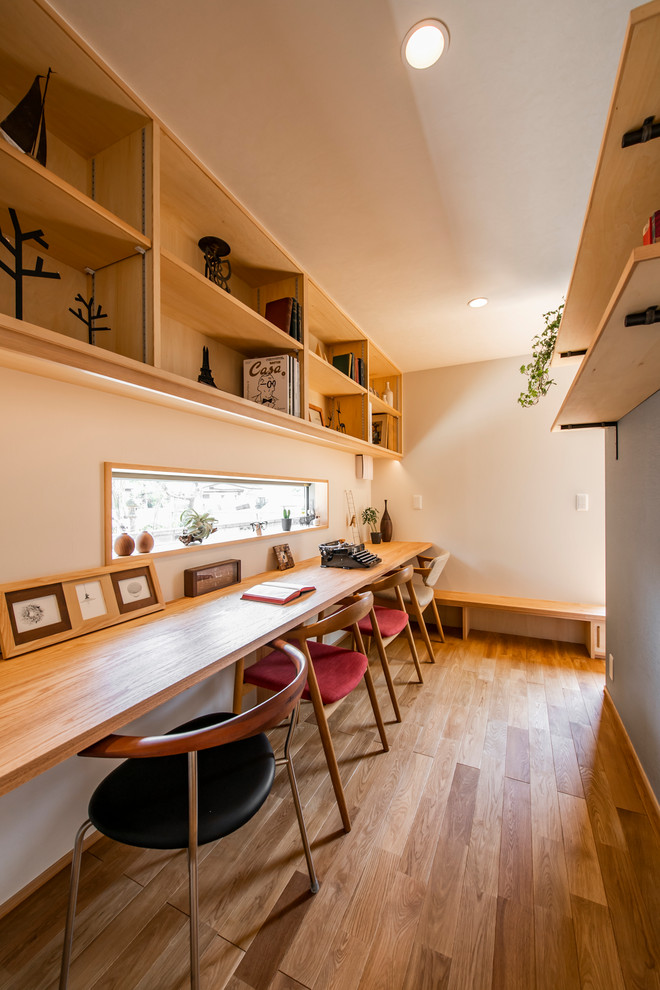 Minimalistisk inredning av ett arbetsrum, med grå väggar, mellanmörkt trägolv, ett inbyggt skrivbord och brunt golv