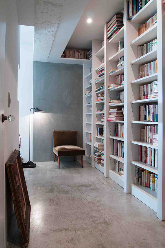 Ejemplo de despacho moderno de tamaño medio sin chimenea con paredes blancas, suelo de cemento y biblioteca