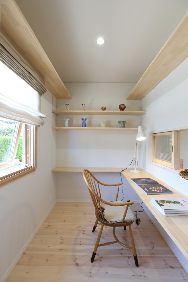Inredning av ett minimalistiskt arbetsrum, med vita väggar, mellanmörkt trägolv, ett inbyggt skrivbord och beiget golv