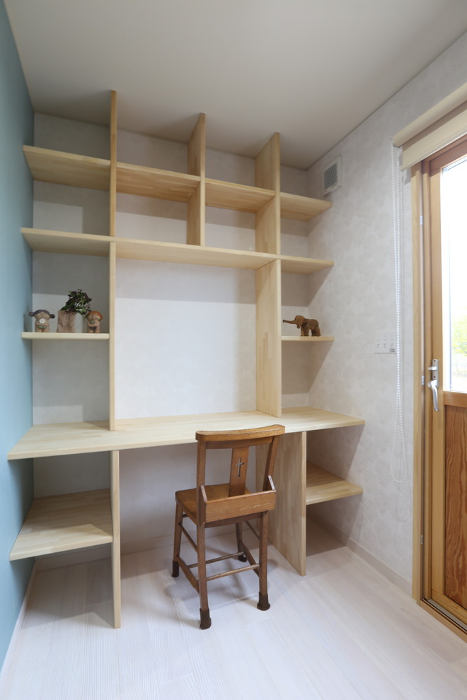 Modelo de despacho de estilo zen con paredes azules, suelo de madera clara y escritorio empotrado
