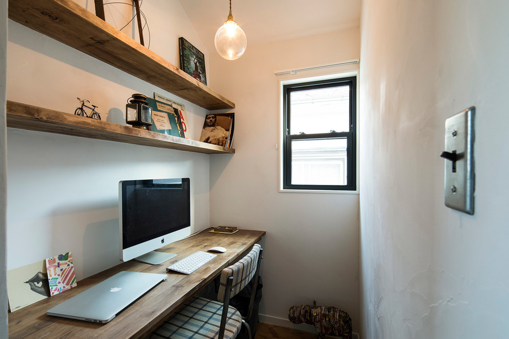 Cette image montre un petit bureau nordique avec un mur blanc et un bureau intégré.