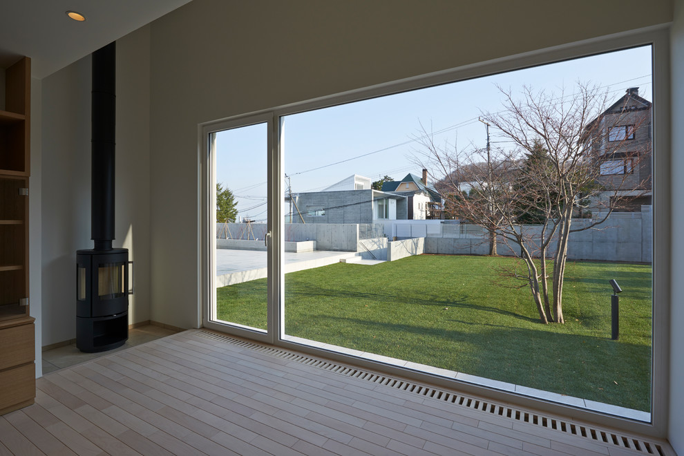 Inspiration för minimalistiska hemmastudior, med vita väggar, ljust trägolv och en öppen vedspis
