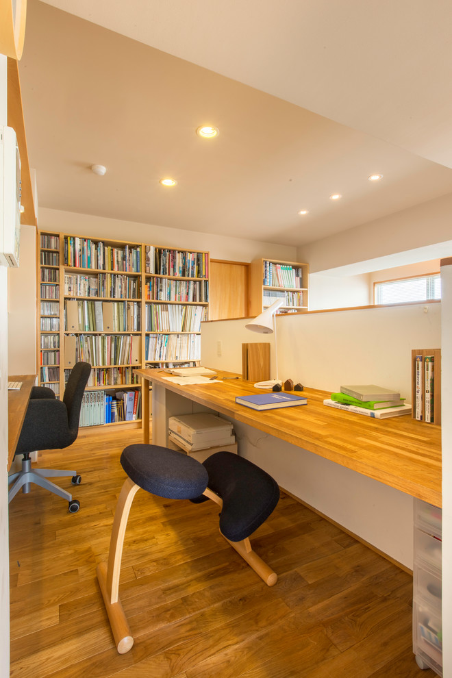 Свежая идея для дизайна: домашняя библиотека в скандинавском стиле с белыми стенами, паркетным полом среднего тона, отдельно стоящим рабочим столом и коричневым полом - отличное фото интерьера