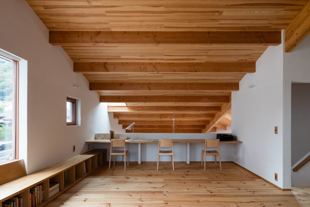 Imagen de despacho costero con paredes blancas, escritorio empotrado, suelo marrón y suelo de madera clara