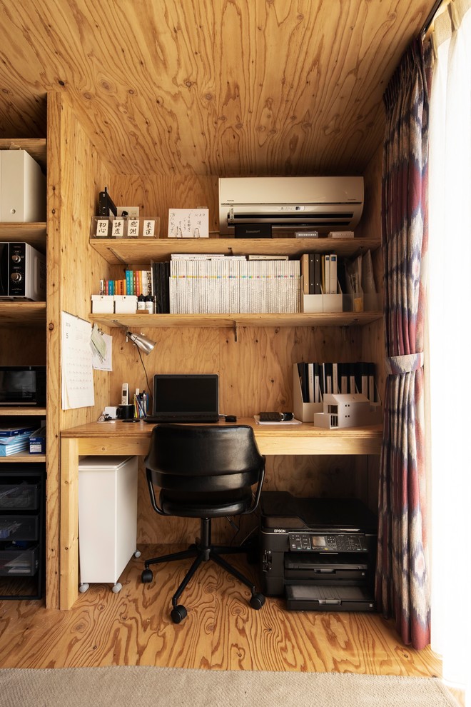 他の地域にある小さなカントリー風のおしゃれなホームオフィス・書斎 (茶色い壁、無垢フローリング、造り付け机、茶色い床) の写真
