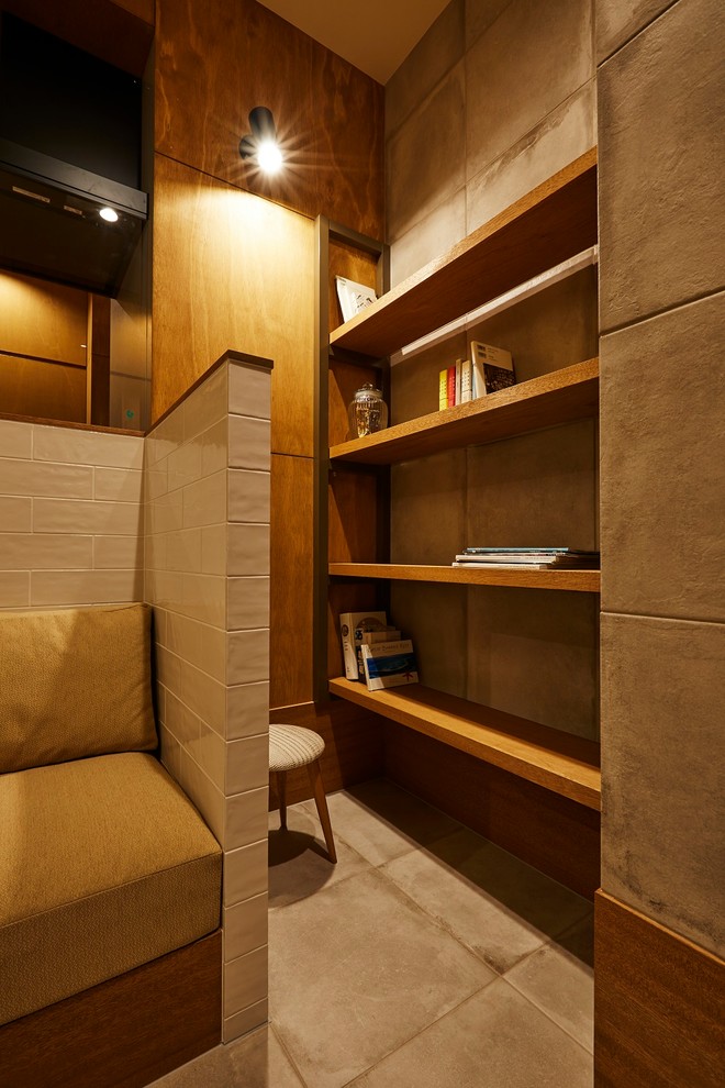 Ejemplo de despacho moderno de tamaño medio con biblioteca, paredes marrones, suelo de baldosas de porcelana, escritorio empotrado y suelo gris