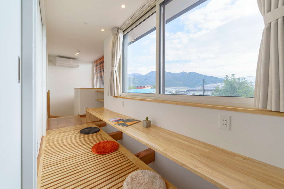 Diseño de despacho asiático pequeño con paredes blancas, suelo de contrachapado, escritorio empotrado y suelo marrón