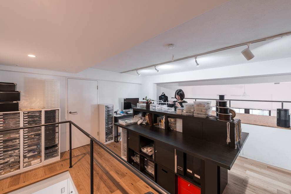 Mittelgroßes Industrial Arbeitszimmer mit Studio, weißer Wandfarbe, Sperrholzboden, freistehendem Schreibtisch und braunem Boden in Tokio