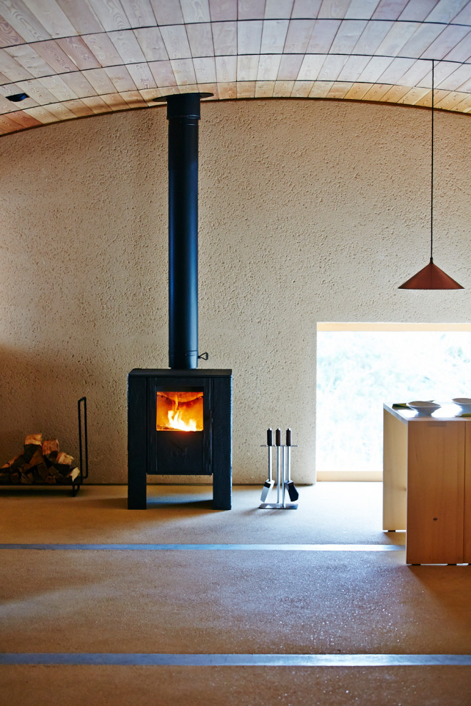 Réalisation d'un bureau minimaliste avec un poêle à bois et un manteau de cheminée en béton.