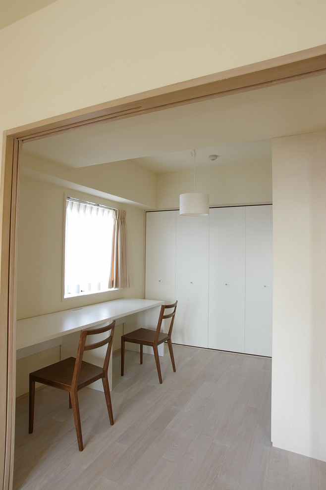 Diseño de despacho escandinavo pequeño sin chimenea con paredes blancas, suelo de madera clara, escritorio empotrado y suelo beige