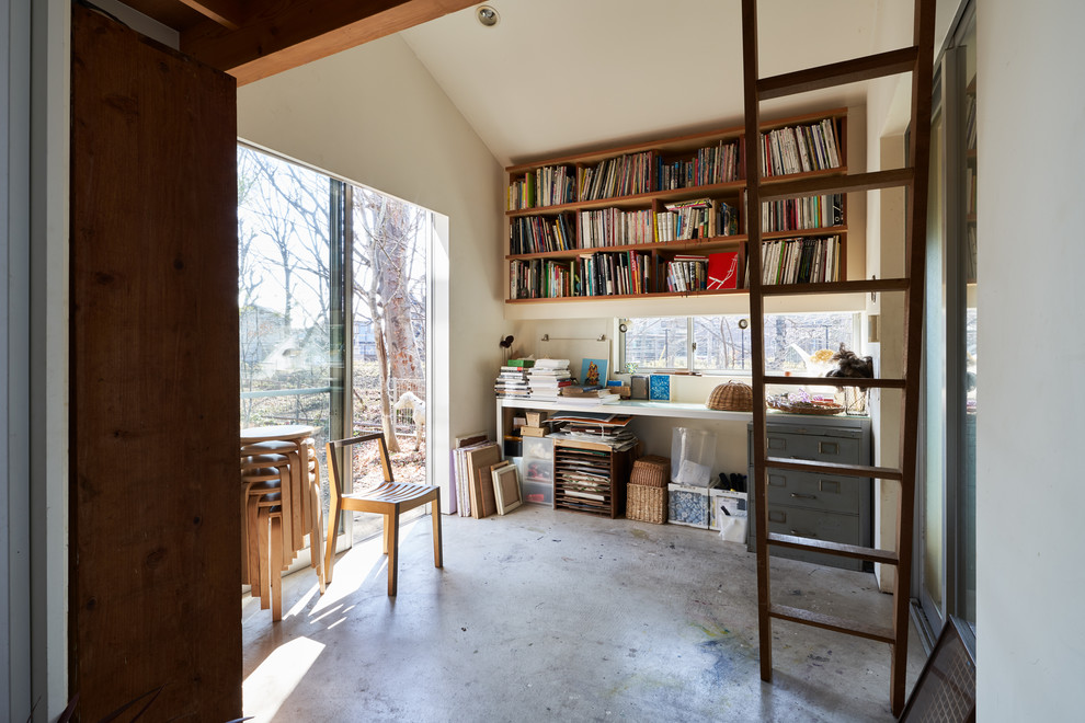 Idéer för att renovera ett litet industriellt hemmastudio, med vita väggar, betonggolv, ett fristående skrivbord och grått golv