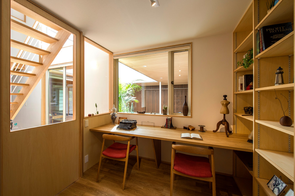 Источник вдохновения для домашнего уюта: кабинет в восточном стиле с белыми стенами, паркетным полом среднего тона, встроенным рабочим столом и коричневым полом