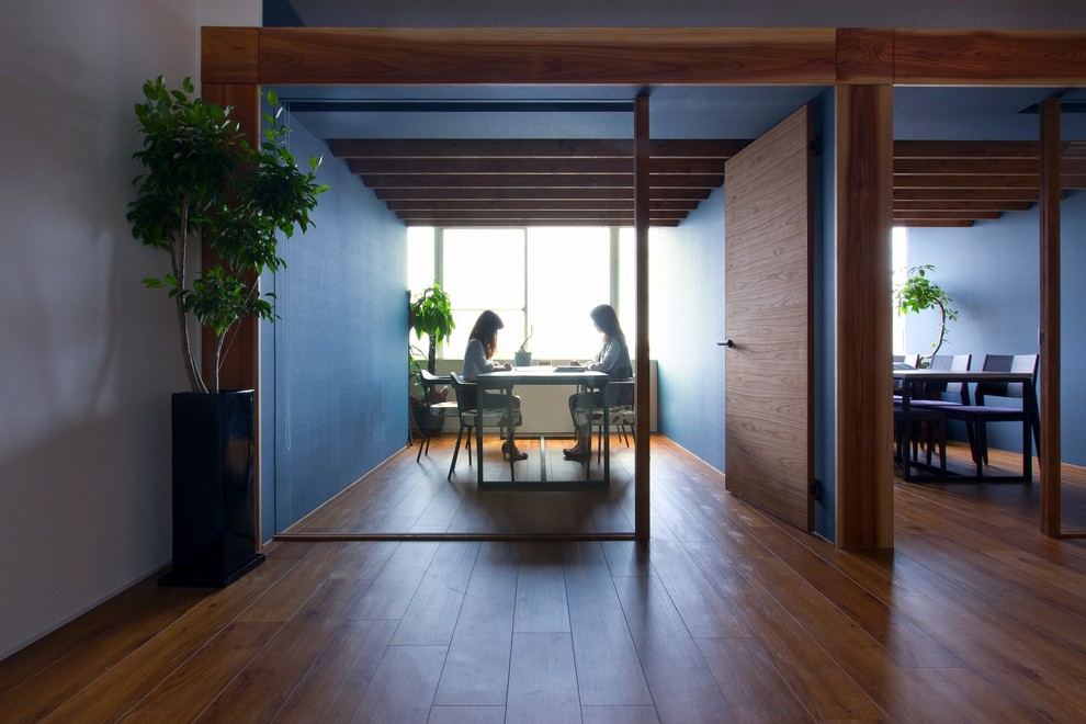 60 tals inredning av ett litet hemmastudio, med blå väggar, vinylgolv, ett fristående skrivbord och beiget golv