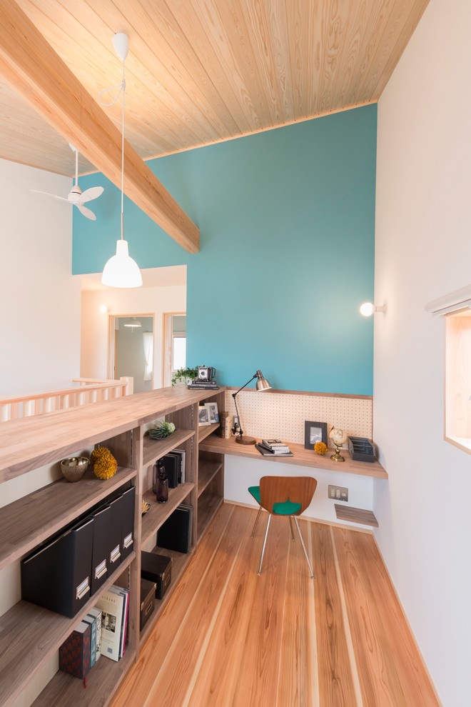 他の地域にある北欧スタイルのおしゃれなホームオフィス・書斎 (造り付け机、青い壁、無垢フローリング、茶色い床) の写真