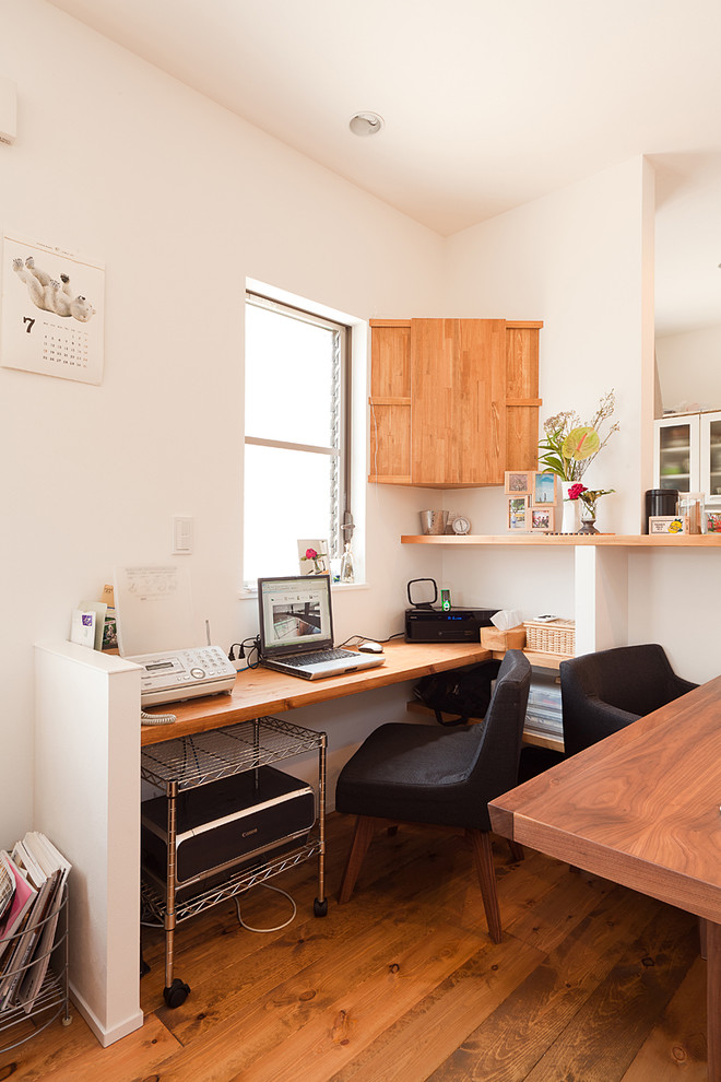Idée de décoration pour un bureau minimaliste avec un mur blanc, un sol en bois brun, un bureau intégré et un sol marron.