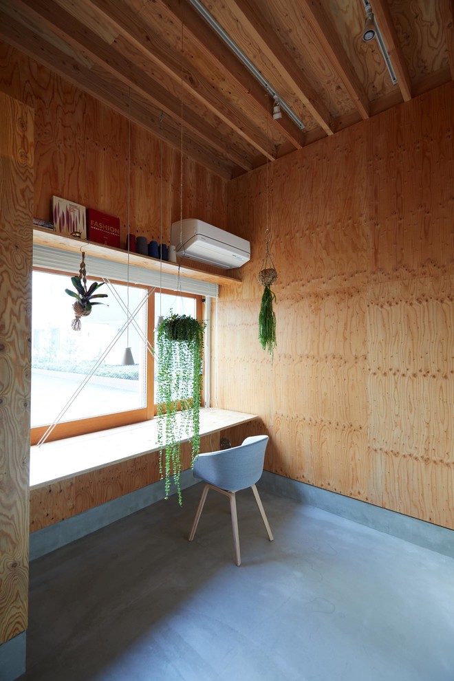 На фото: маленькая домашняя мастерская в восточном стиле с встроенным рабочим столом, коричневыми стенами, бетонным полом и серым полом для на участке и в саду с