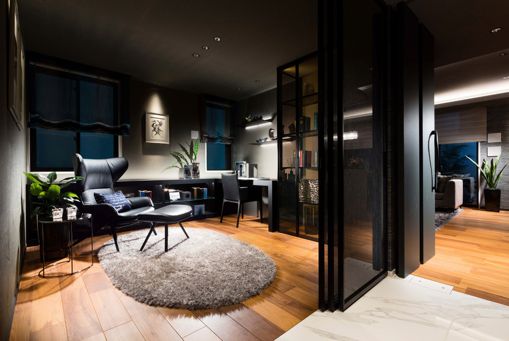 Modernes Arbeitszimmer ohne Kamin mit Arbeitsplatz, grauer Wandfarbe, braunem Holzboden, freistehendem Schreibtisch und braunem Boden in Tokio