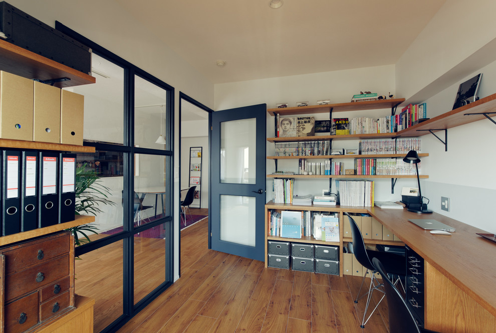 Immagine di un ufficio moderno con pareti bianche, pavimento in legno massello medio e scrivania incassata