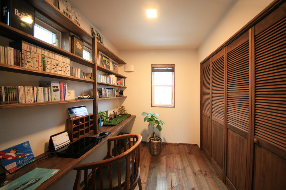 Idee per uno studio etnico con pareti bianche, pavimento in legno massello medio, scrivania incassata e pavimento marrone