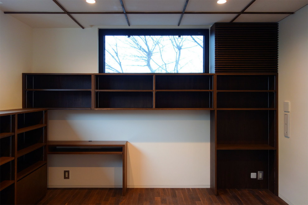 Idee per un ufficio con pareti bianche, parquet scuro e scrivania incassata