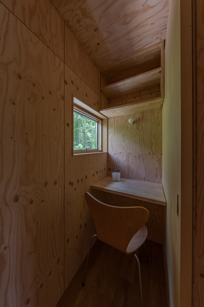 Inspiration för små industriella hemmabibliotek, med beige väggar, mellanmörkt trägolv, ett inbyggt skrivbord och beiget golv