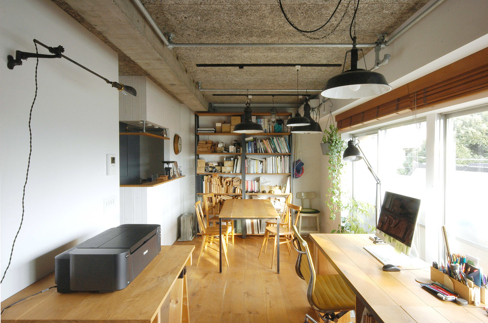 Immagine di un atelier industriale con pareti bianche, pavimento in legno massello medio e scrivania autoportante