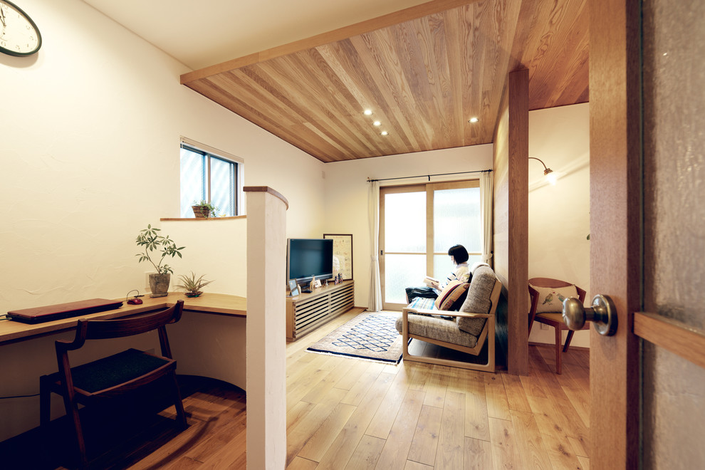 Modelo de despacho pequeño con paredes blancas, suelo de madera en tonos medios y escritorio empotrado