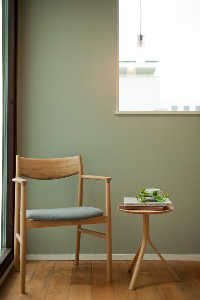 Стильный дизайн: рабочее место в скандинавском стиле с зелеными стенами, отдельно стоящим рабочим столом и паркетным полом среднего тона - последний тренд