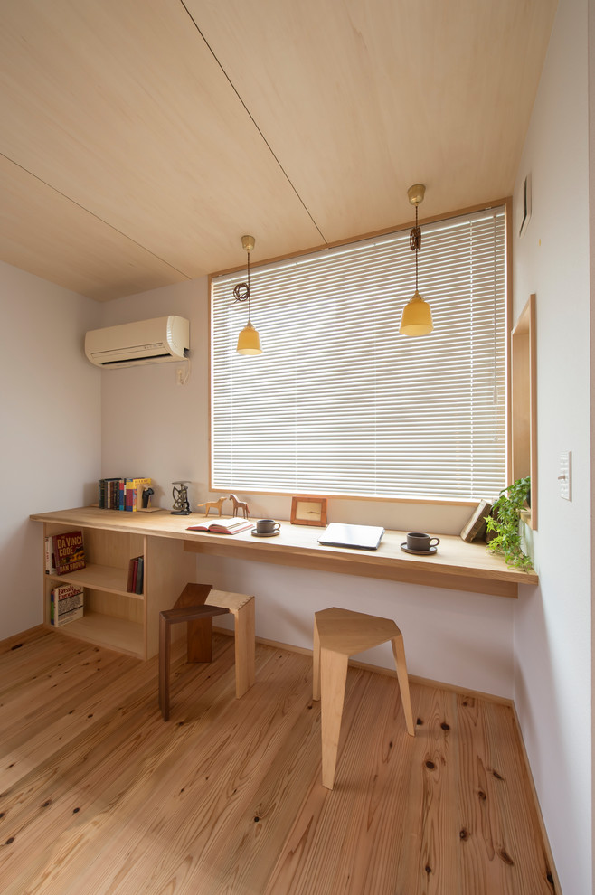 Immagine di uno studio etnico con pareti bianche, pavimento in legno massello medio, scrivania incassata e pavimento marrone