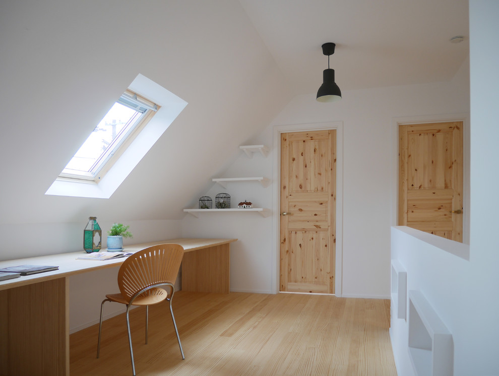 Inredning av ett minimalistiskt arbetsrum, med vita väggar, ljust trägolv, ett inbyggt skrivbord och beiget golv