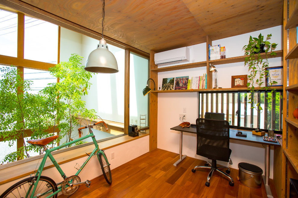 Cette photo montre un bureau asiatique de type studio avec un mur blanc, un sol en bois brun, aucune cheminée et un bureau indépendant.