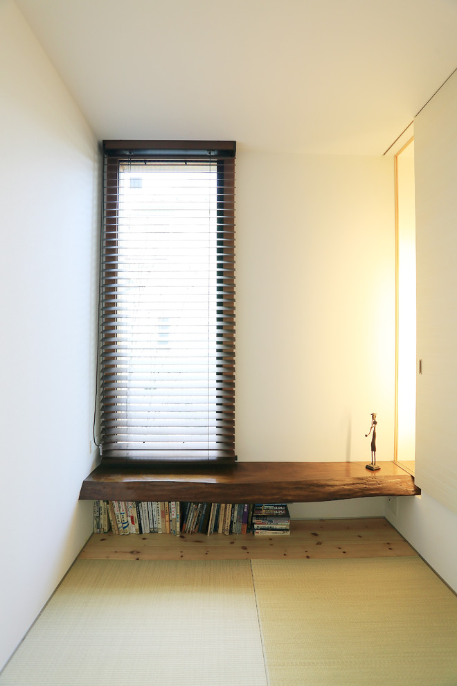 This is an example of a small world-inspired study in Tokyo with white walls, tatami flooring and a built-in desk.
