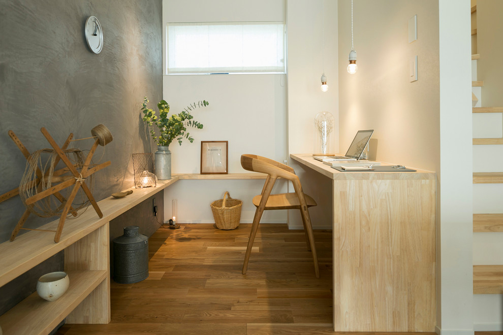 Cette image montre un petit bureau nordique avec un mur gris, un sol en bois brun, un bureau intégré et un sol marron.