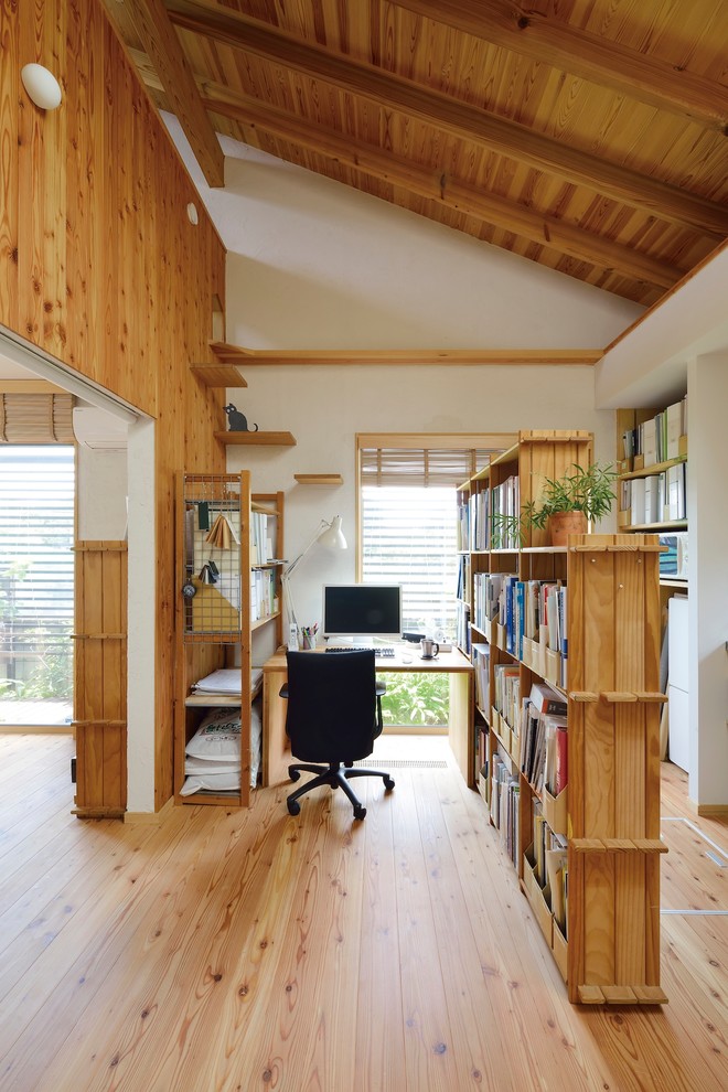 Kleines Uriges Arbeitszimmer mit Studio, weißer Wandfarbe, braunem Holzboden, Kaminofen, Kaminumrandung aus Beton, freistehendem Schreibtisch und beigem Boden in Tokio Peripherie