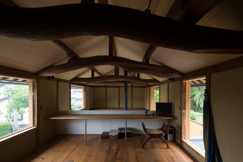 Inspiration pour un bureau traditionnel de taille moyenne avec un mur beige, un sol en bois brun, un poêle à bois, un manteau de cheminée en béton, un bureau intégré, un sol marron et poutres apparentes.