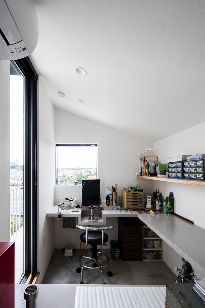Imagen de despacho actual con paredes blancas, suelo de cemento, escritorio empotrado y suelo gris