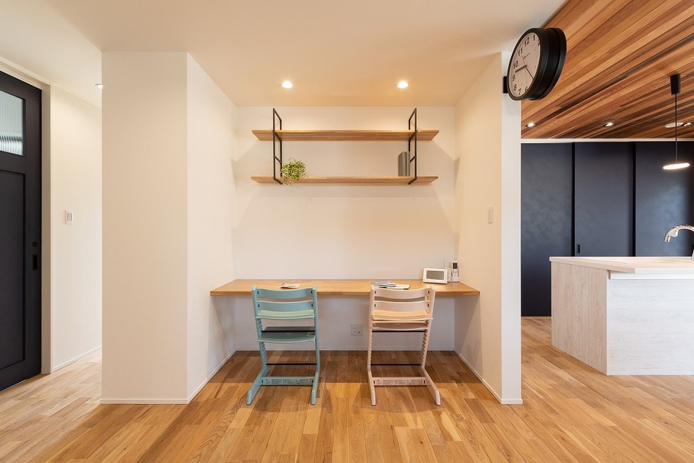 Ejemplo de despacho actual pequeño con paredes blancas, suelo de madera en tonos medios, escritorio empotrado y suelo marrón