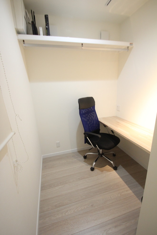 Réalisation d'un bureau minimaliste avec un mur blanc, un sol en contreplaqué, un bureau intégré et un sol beige.