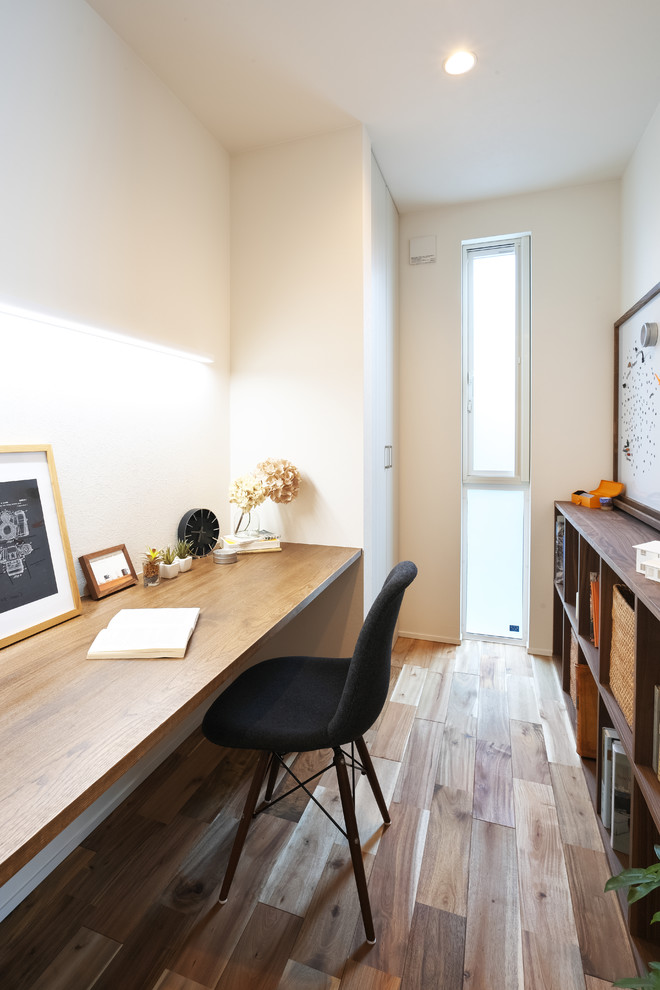 Ejemplo de despacho moderno con biblioteca, paredes blancas, suelo de madera oscura y suelo marrón