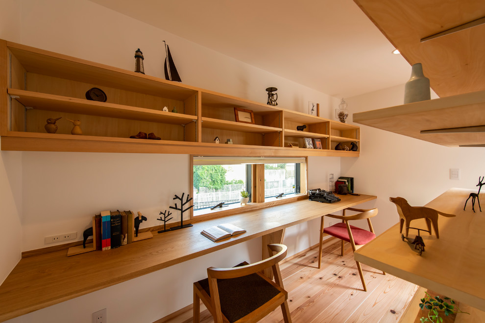 Idéer för att renovera ett skandinaviskt arbetsrum, med vita väggar, mellanmörkt trägolv och ett inbyggt skrivbord