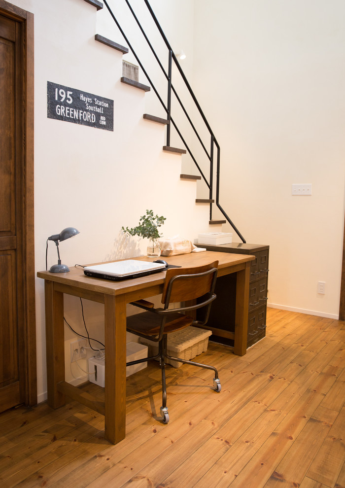 Modelo de despacho de estilo de casa de campo con paredes blancas, suelo de madera en tonos medios, escritorio independiente y suelo marrón