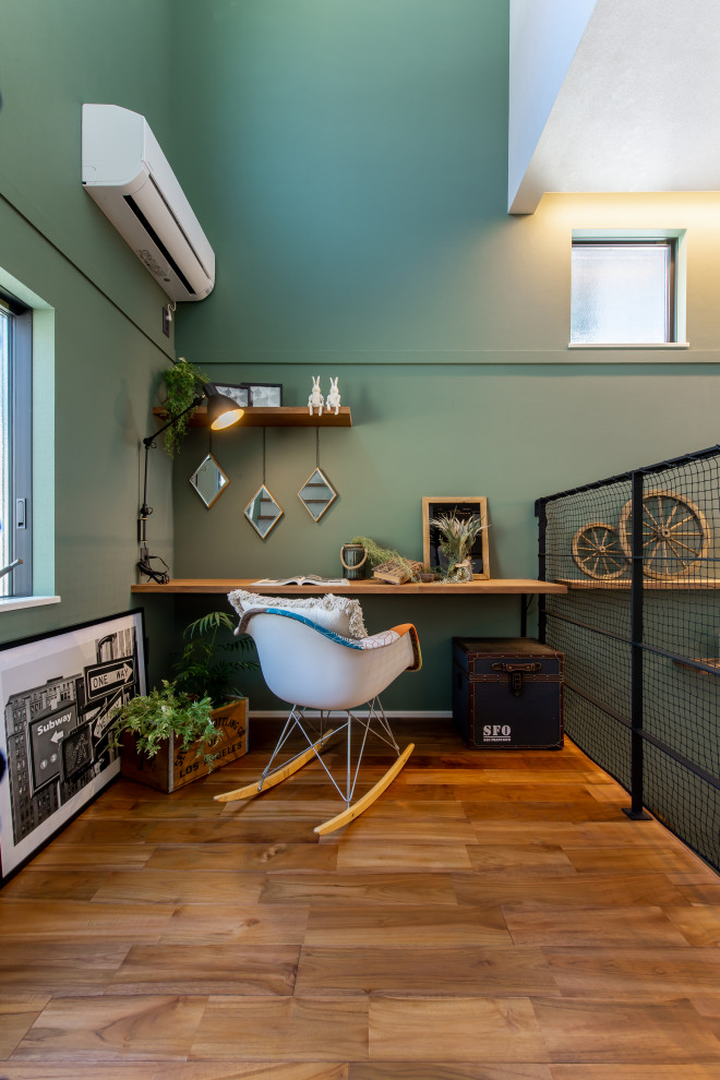 Mittelgroßes Arbeitszimmer mit Arbeitsplatz, grüner Wandfarbe, braunem Holzboden, Einbau-Schreibtisch, Tapetendecke und Tapetenwänden in Sonstige