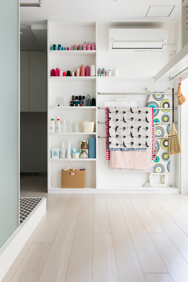 Cette image montre un petit bureau minimaliste de type studio avec un mur blanc, un sol en contreplaqué, aucune cheminée, un bureau indépendant et un sol blanc.