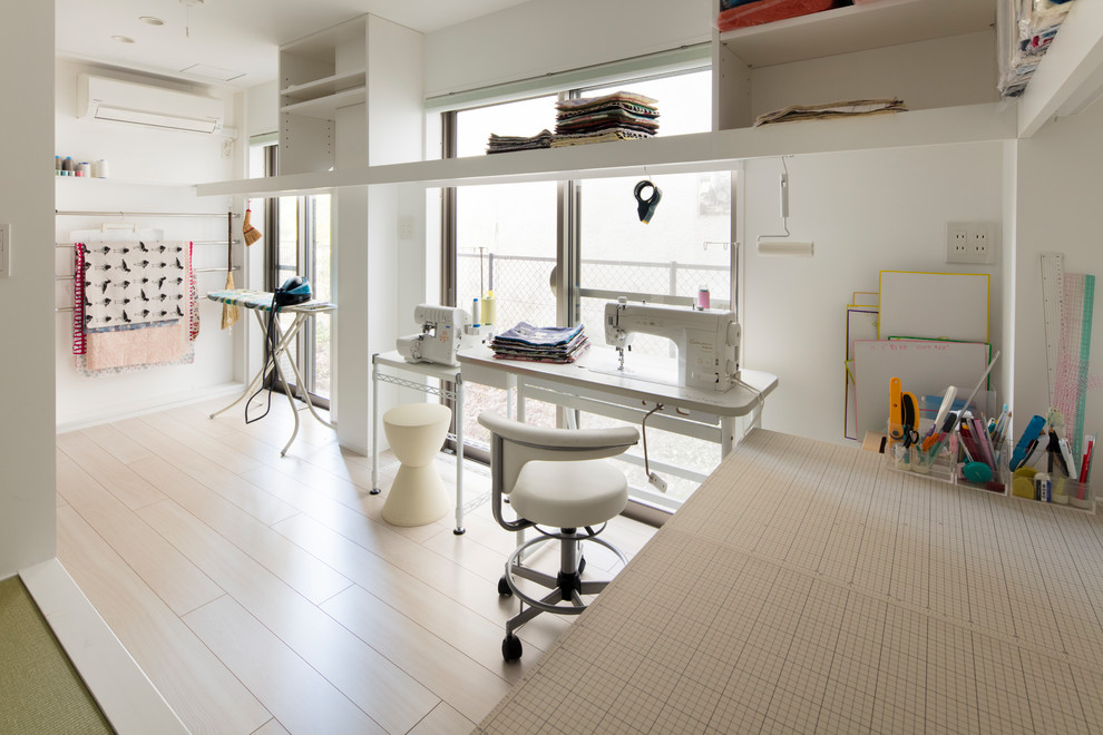 На фото: маленькая домашняя мастерская в стиле модернизм с белыми стенами, полом из фанеры, отдельно стоящим рабочим столом и белым полом без камина для на участке и в саду