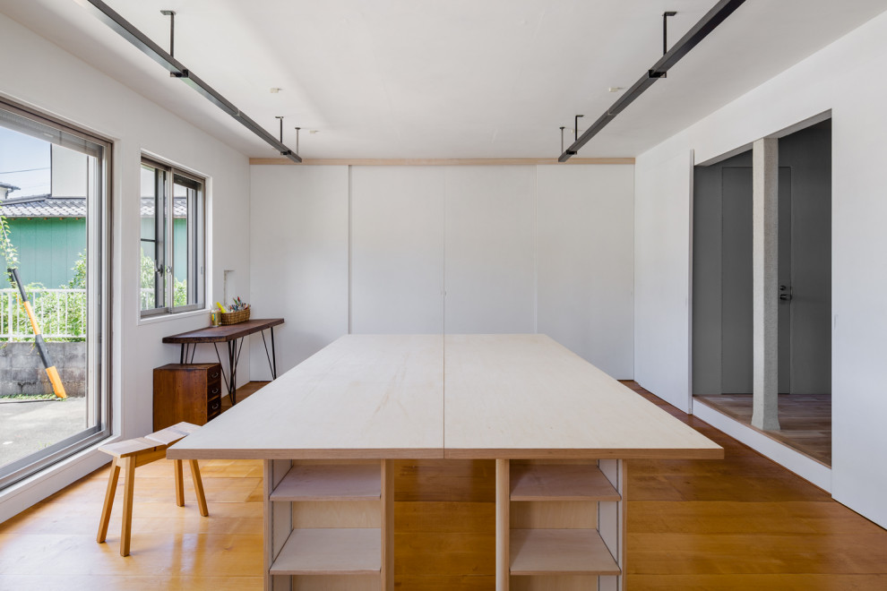 Foto di un atelier etnico di medie dimensioni con pareti bianche, pavimento in compensato, nessun camino, scrivania autoportante e pavimento marrone