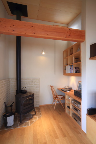 Idée de décoration pour un bureau champêtre avec un mur beige, un sol en bois brun, un poêle à bois, un manteau de cheminée en carrelage, un bureau intégré, un sol beige et un plafond en bois.