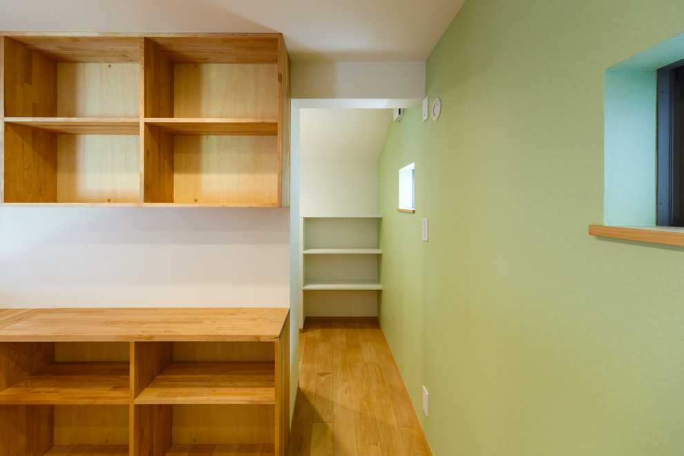 Idées déco pour un bureau moderne avec un mur vert, un sol en bois brun, aucune cheminée, un bureau intégré et un sol beige.
